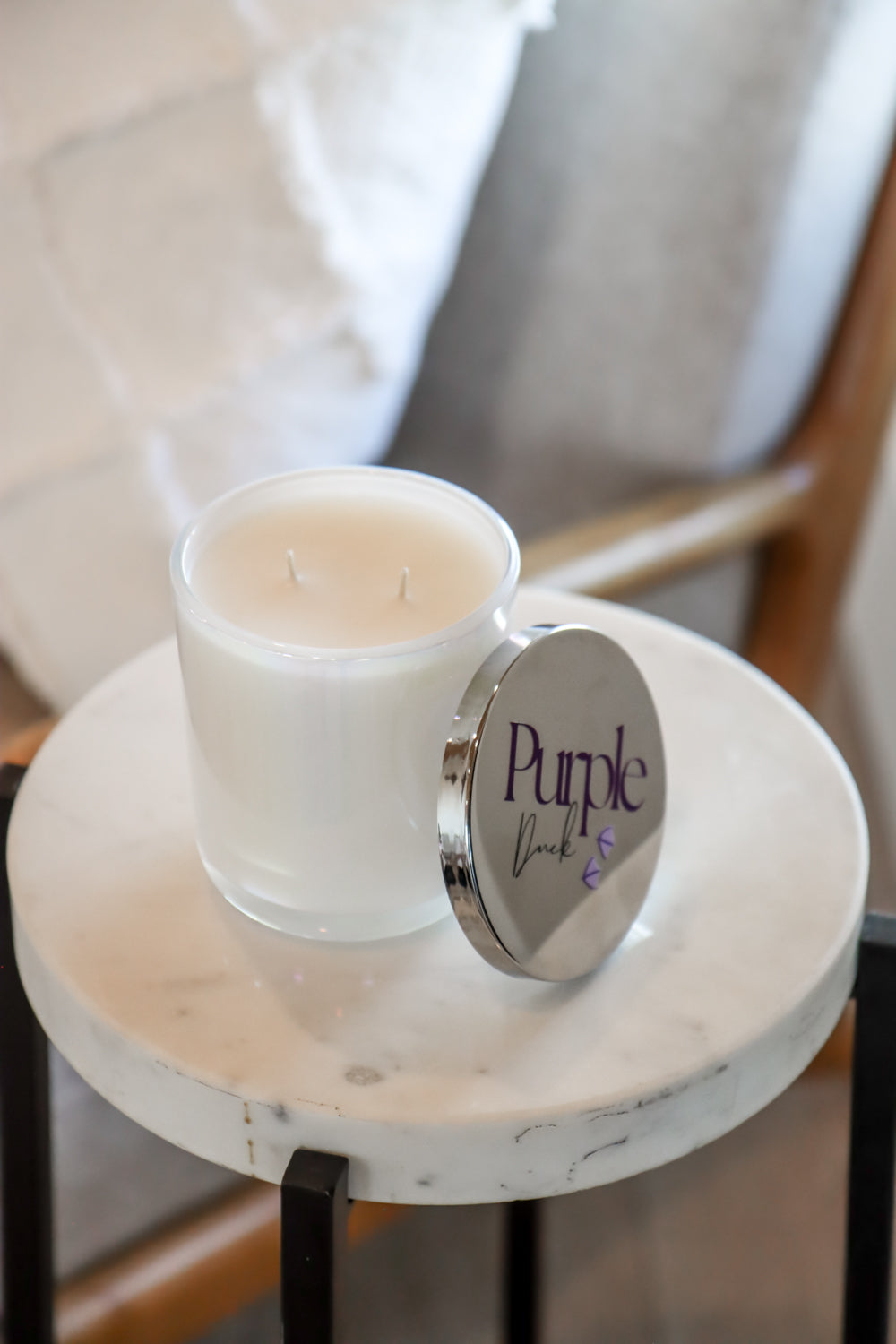 Frosted glass candle with purple wick on a marble surface.