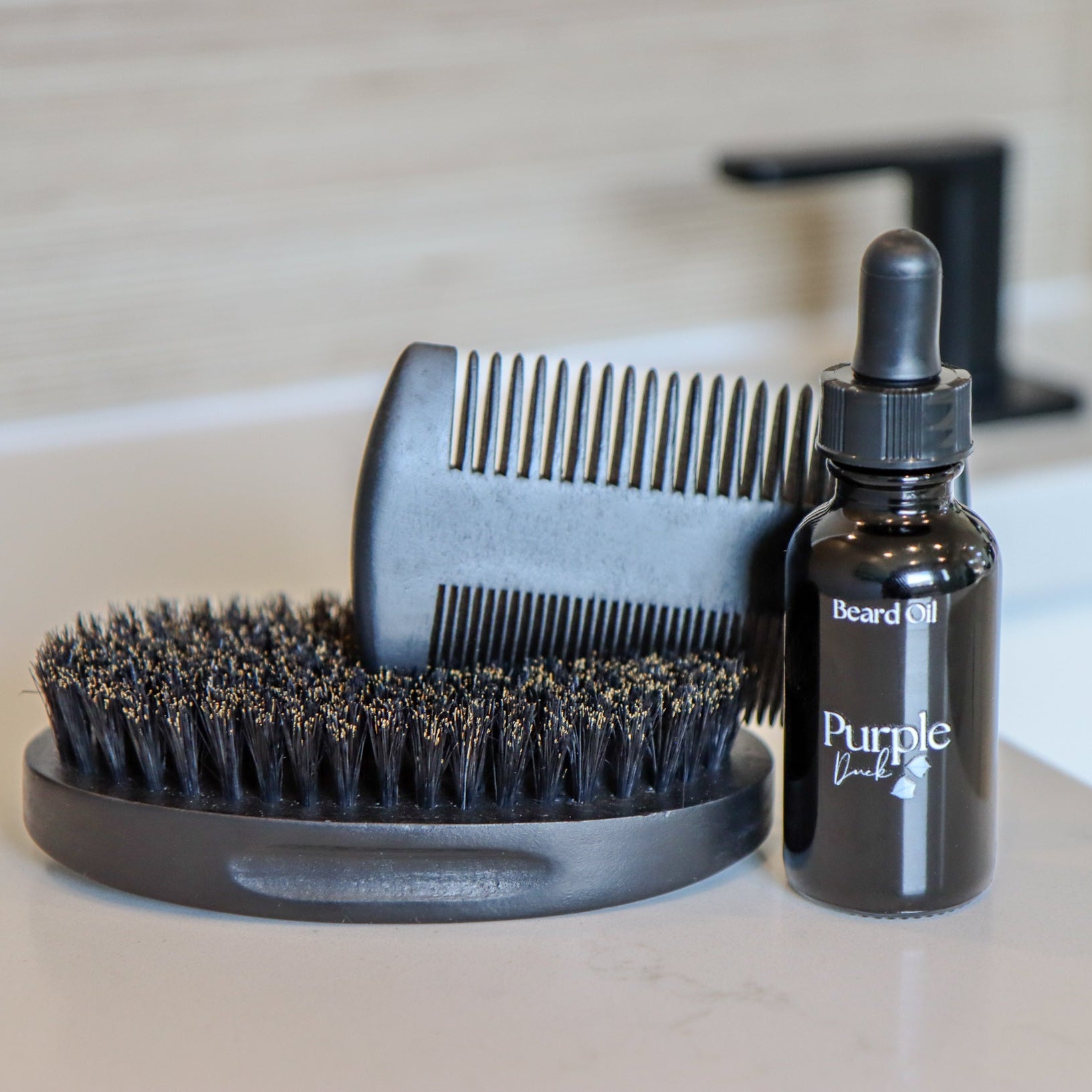 Beard grooming set with brush, comb, and bottle on a bathroom counter.