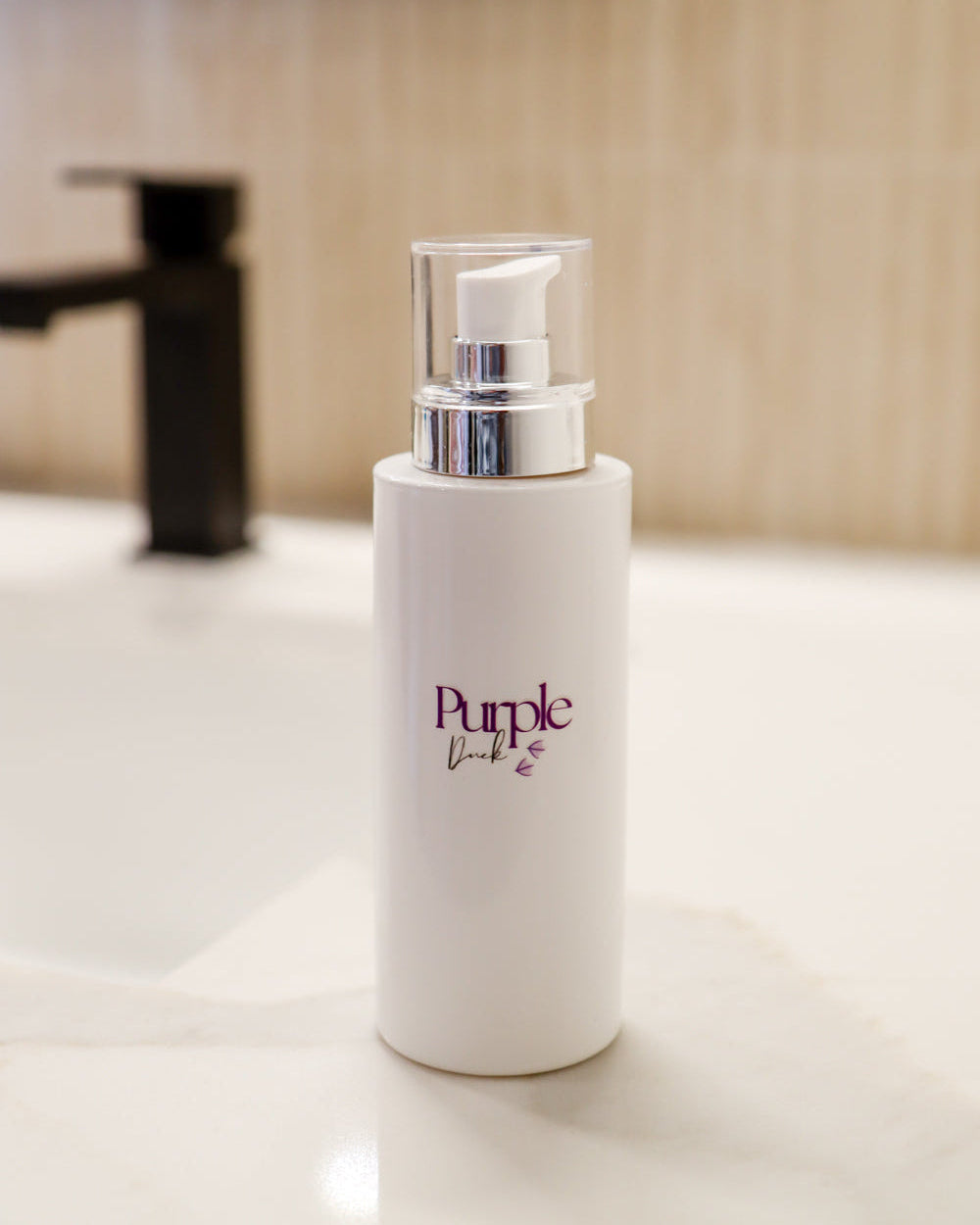 A pump bottle of body lotion with the brand 'Purple Duck' displayed on a bathroom counter.