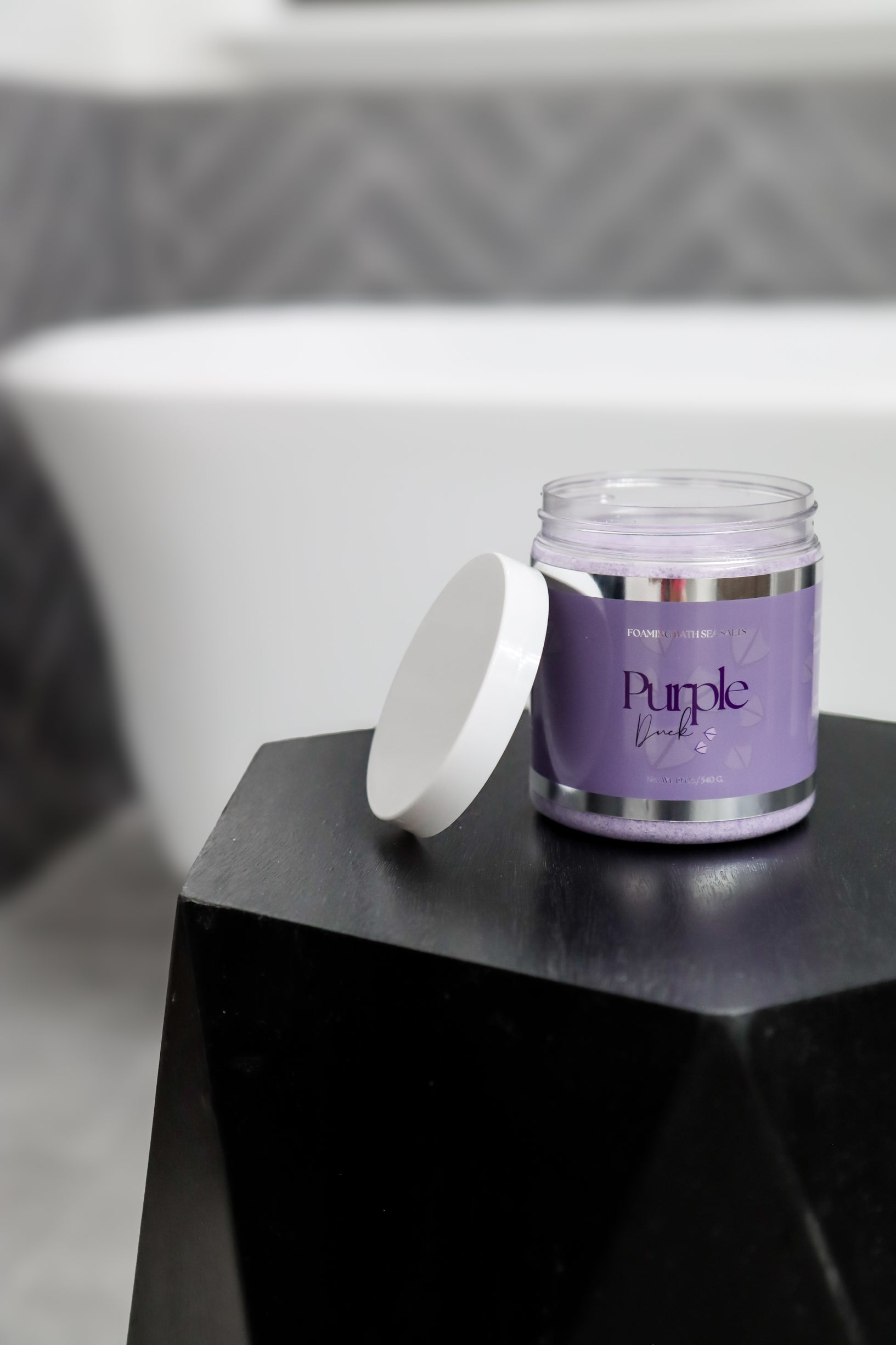 Purple duck bath salts sitting next to a bath tub
