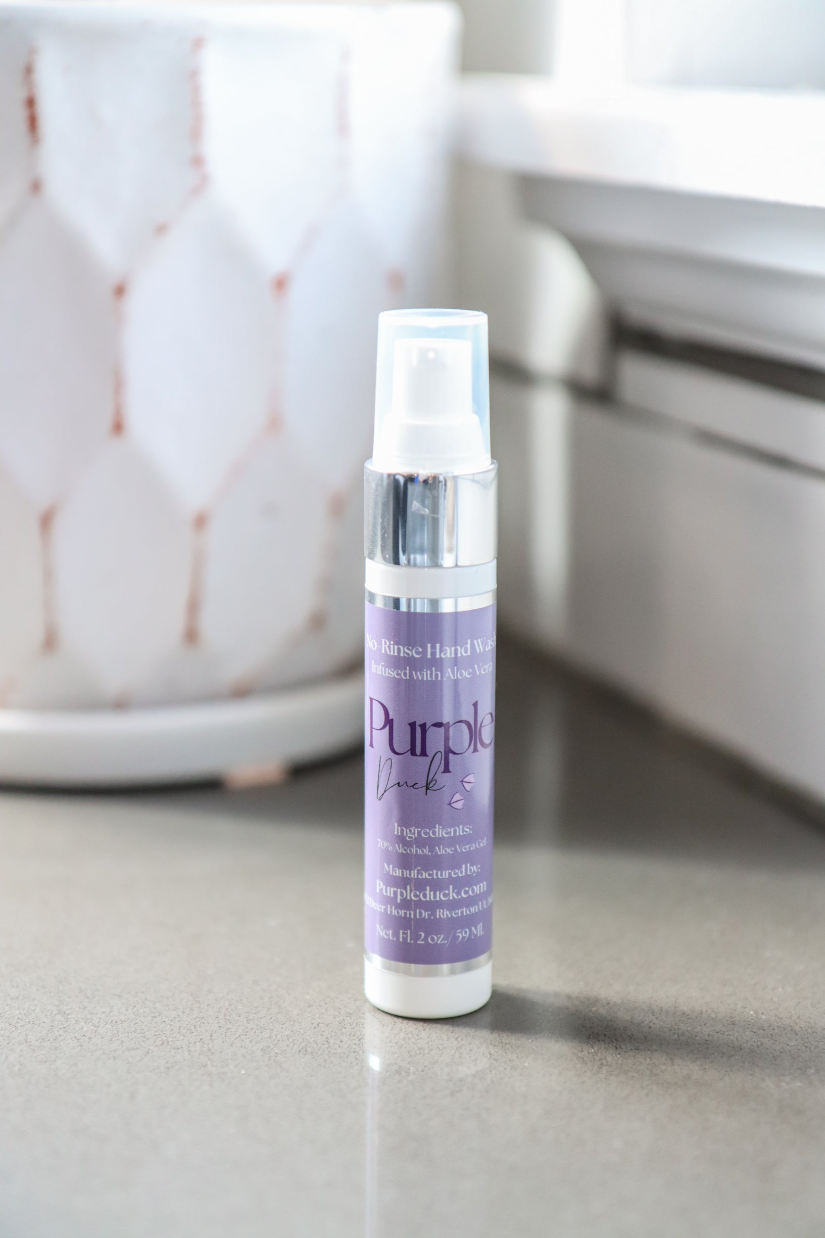 Purple bottle of hand sanitizer on a gray surface with a blurred background