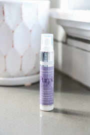 Purple bottle of hand sanitizer on a gray surface with a blurred background