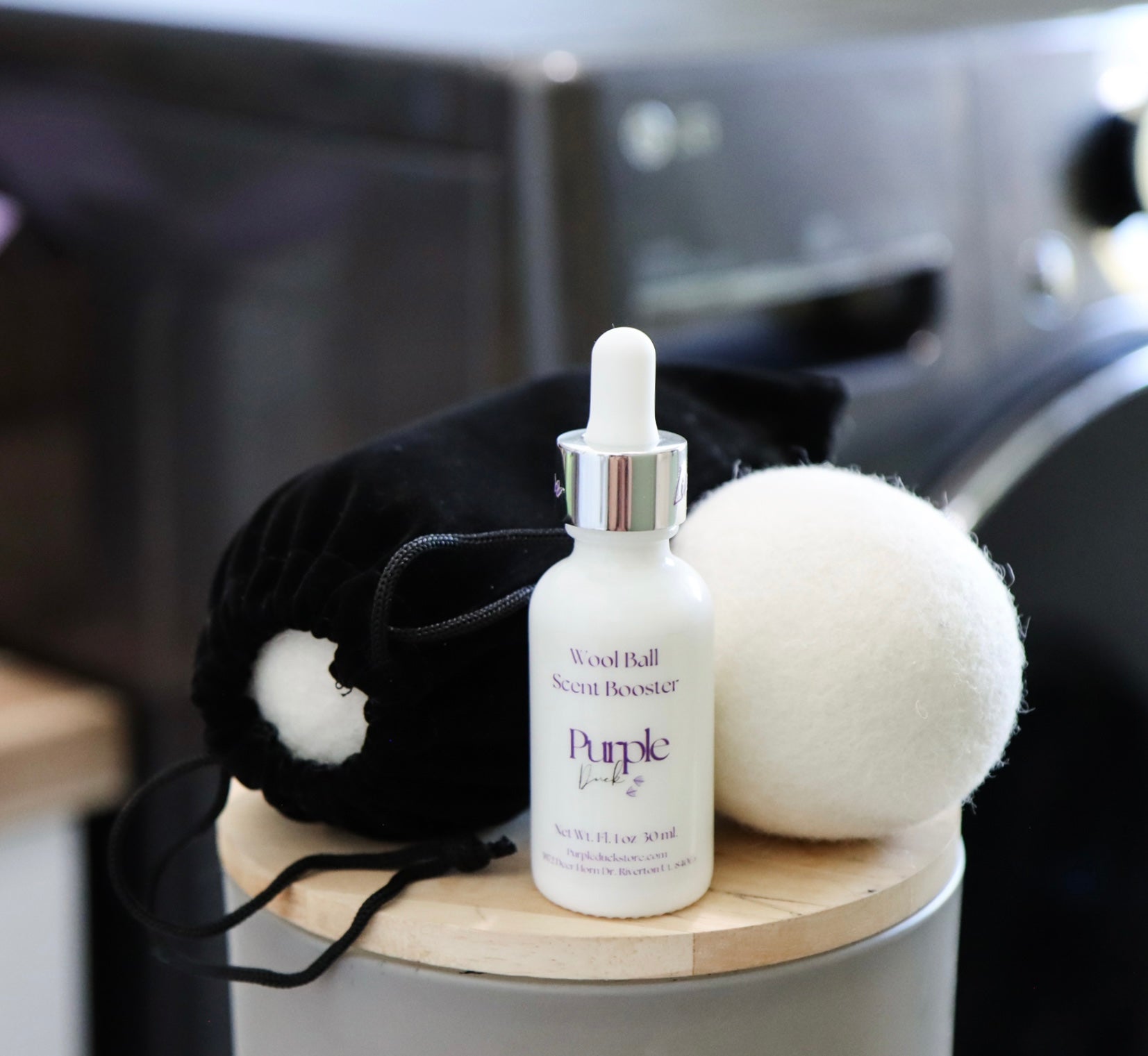 White bottle labeled 'Purple' on a wooden surface with a white cotton and a mini black cloth bag in the background