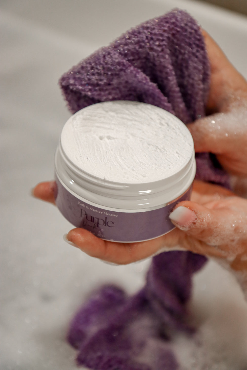 Women using bath and shower mousse with the purple rag 