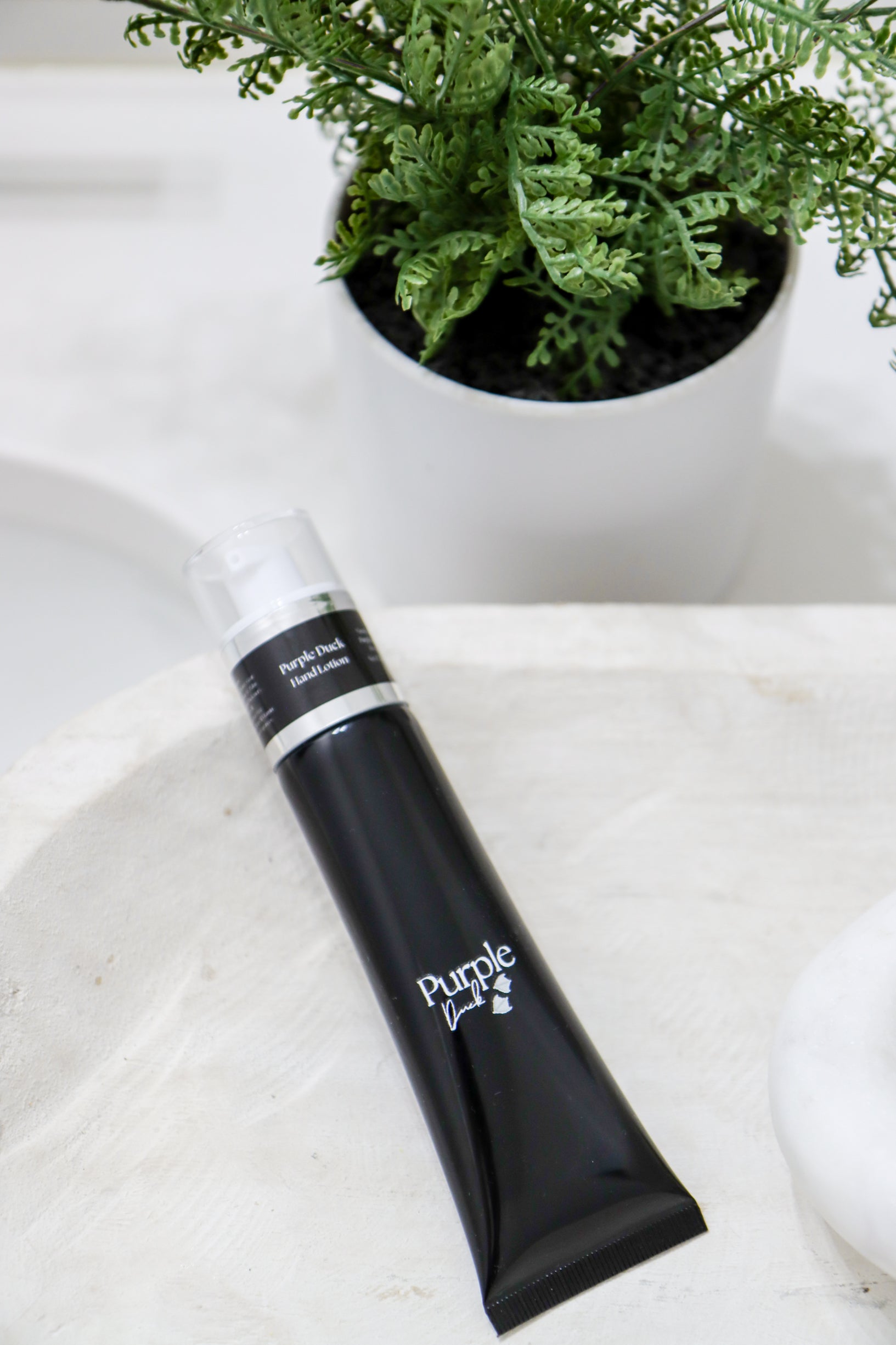 Purple Duck Goats Milk Men's Hand Lotion sitting on a white counter