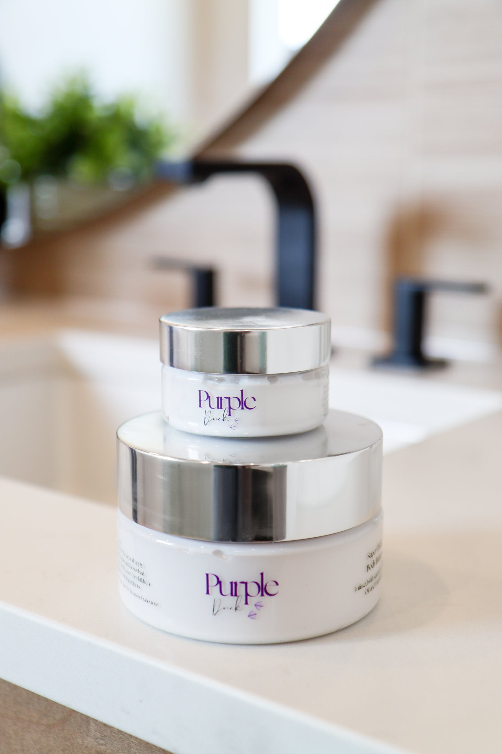 A small and medium size container of purple duck body cream