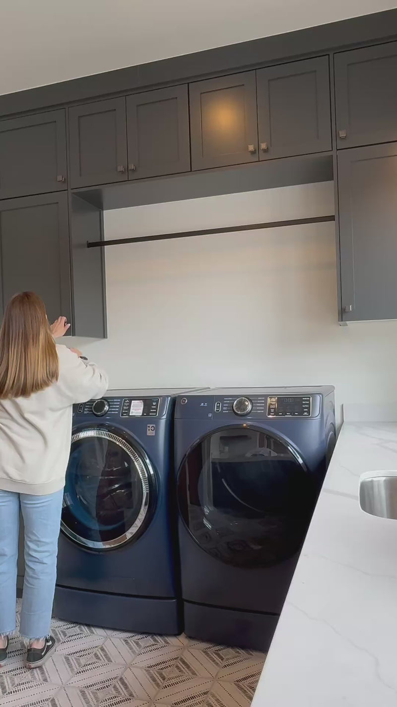 Girl standing in front of two front-loading washing machines, appearing to do laundry.